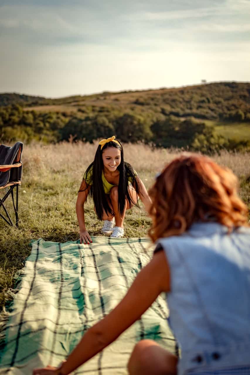 two girls enjoying a sober picnic outdoors on a blanket