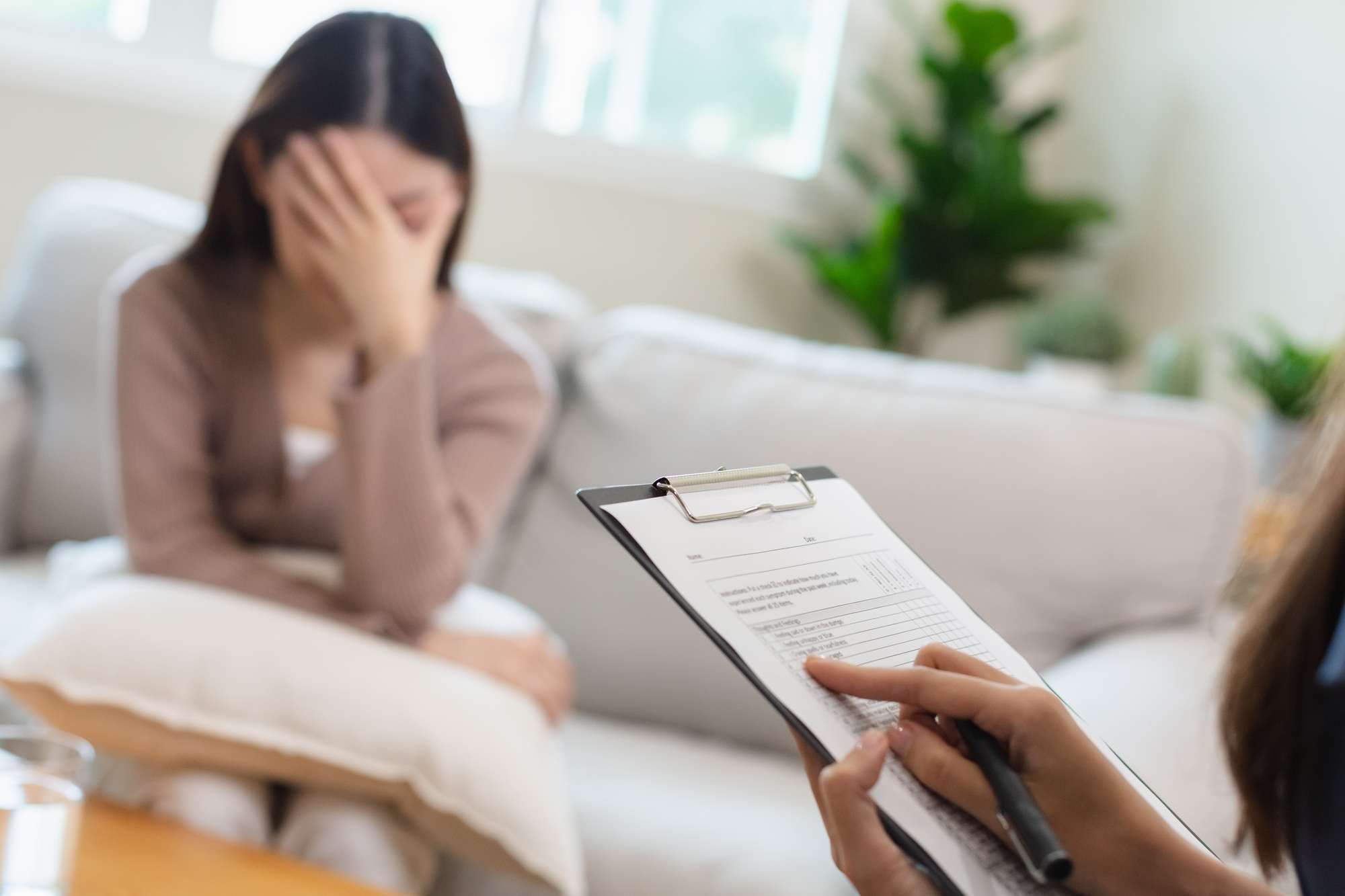 Psychiatrist taking notes examining female patients therapy for mental symptoms and depression.